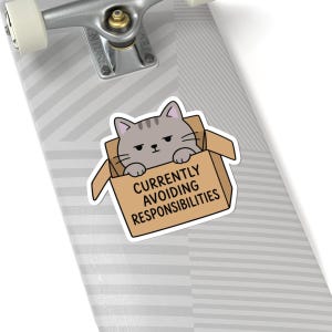 May include: A sticker featuring a grey tabby cat sitting inside a brown cardboard box. The cat has a neutral expression and its paws rest on the edge of the box. The text on the front of the box reads, CURRENTLY AVOIDING RESPONSIBILITIES.
