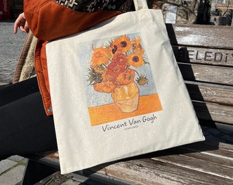 May include: A white canvas tote bag with a painting of sunflowers in a vase. The painting is by Vincent Van Gogh and the text "SUNFLOWER" is printed below the artist's name.