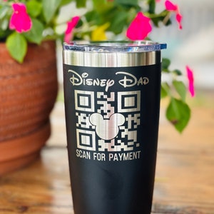 May include: Black insulated tumbler with a silver rim and lid. The tumbler features the text "Disney Dad" above a QR code with a Mickey Mouse head in the center, and the words "SCAN FOR PAYMENT" below.