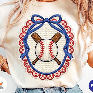 May include: Cream-coloured sweatshirt with a baseball design. The design features a baseball with red stitching, crossed brown bats, and a blue ribbon within a red scalloped border. The design is centred on the front of the shirt.