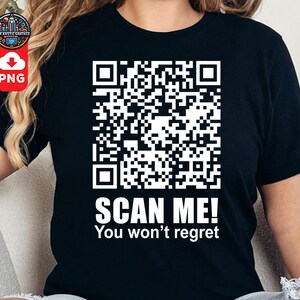 Pode incluir: Camiseta preta com um código QR branco e o texto "SCAN ME! You won't regret" impresso na frente.