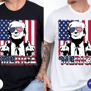 May include: Black and white t-shirts with a graphic design featuring a person wearing sunglasses with an American flag design. The design includes the word "'MERICA" in red, white, and blue.