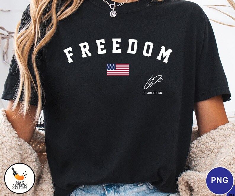 May include: Black t-shirt with the word "FREEDOM" in white arched letters above a small American flag. Below the flag is a signature and the name "CHARLIE KIRK".