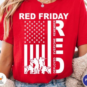 以下が含まれることがあります： アメリカ国旗と兵士の白いグラフィックが特徴の赤いTシャツ。「RED FRIDAY」の文字が上部にあり、「REMEMBER EVERYONE DEPLOYED」が側面にあります。