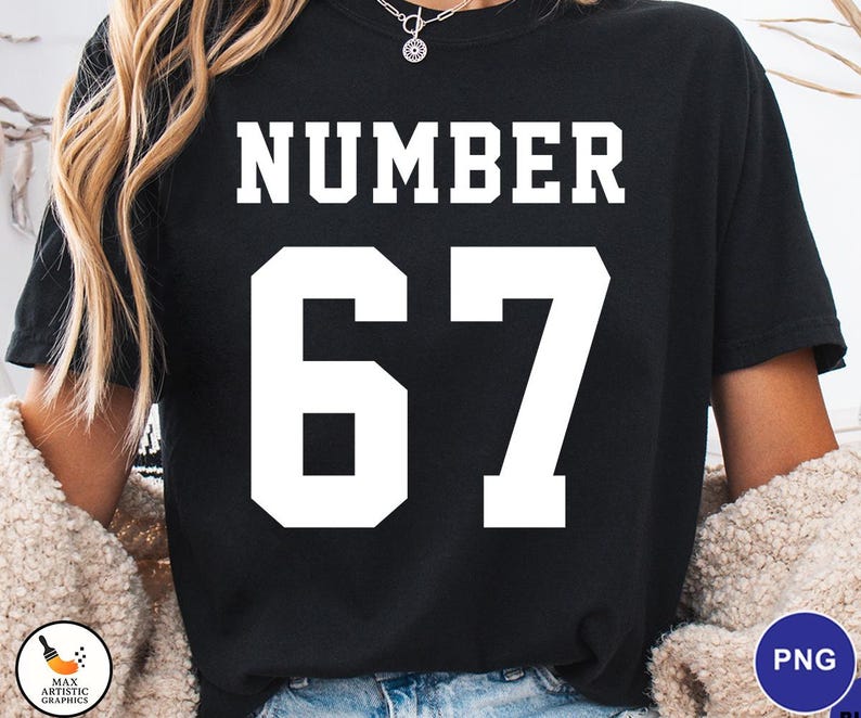 Op de afbeelding: Zwart T-shirt met het woord "NUMBER" in witte blokletters boven het witte nummer "67". Het shirt heeft een ronde hals. Er is een klein logo zichtbaar in de linker benedenhoek.