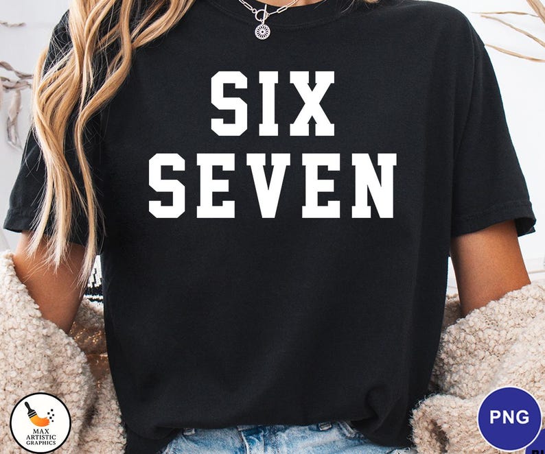 Op de afbeelding: Zwart T-shirt met de woorden "SIX SEVEN" in grote, witte blokletters. Het shirt heeft een ronde hals. Het model draagt een cr&egrave;me-kleurige trui.
