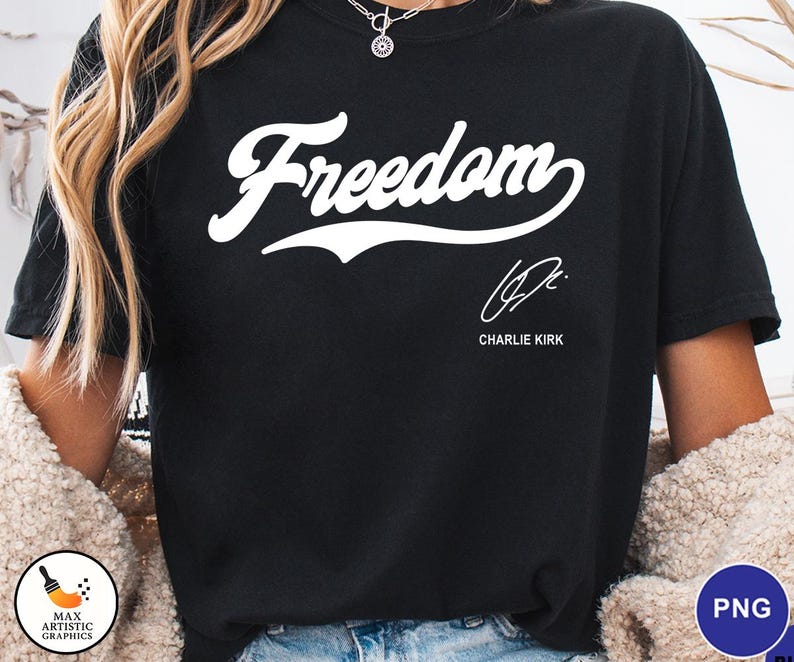 May include: Black t-shirt with the word "Freedom" in a white script font. Below the word is a signature and the name "Charlie Kirk" in a smaller font. The shirt is a solid black color.