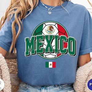 May include: A blue short-sleeve t-shirt featuring a graphic of a soccer ball colored with the green, white, and red of the Mexican flag. The word MEXICO is printed in large green letters with a white outline. A small Mexican flag is below the text.
