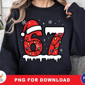 Puede incluir: Sudadera negra con un diseño festivo que presenta el número 67 en rojo, adornado con luces navideñas y un gorro de Papá Noel. Copos de nieve blancos y una base nevada completan el tema navideño. La parte inferior de la imagen tiene el texto "PNG FOR DOWNLOAD".