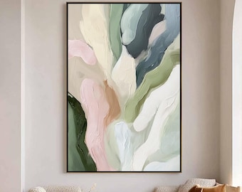 Puede incluir: Obra de arte abstracta enmarcada en negro, que representa formas fluidas en tonos verdes, rosas, blancos y beige. La pintura cuelga en un salón moderno con una mesa de centro de madera y una gran ventana.