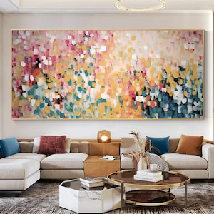May include: Abstract painting with a colorful, textured design. The painting features a variety of colors, including pink, yellow, blue, and green. The painting is displayed on a wall in a living room setting.