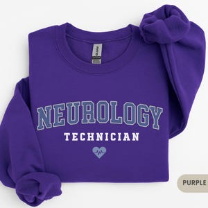 May include: Purple sweatshirt with the text "NEUROLOGY TECHNICIAN" in white and a small blue heart with a heartbeat symbol.
