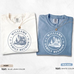 May include: Two short-sleeve t-shirts, one ivory and one blue jean, each featuring a circular graphic with a cabin, pine trees, and the text WILLIAMS FAMILY REUNION ESTD 2026. The ivory shirt has blue jean colored text, and the blue jean shirt has white text.