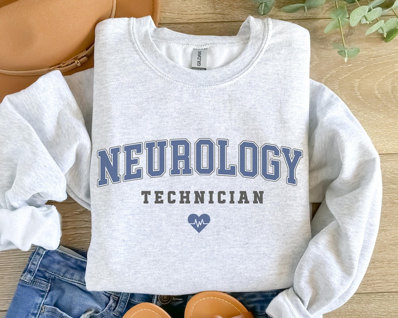 May include: A gray sweatshirt with the text "NEUROLOGY TECHNICIAN" in blue and black lettering. A small blue heart with a heartbeat symbol is below the text.