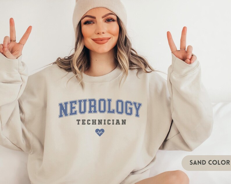 May include: A sand-colored sweatshirt with the text "NEUROLOGY TECHNICIAN" in blue lettering and a small blue heart with a heartbeat symbol.