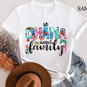 May include: White t-shirt with a colorful graphic design featuring the text "Ohana means family" with Stitch and other Disney characters.