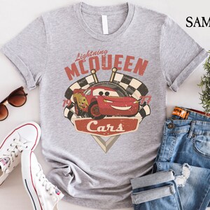 Op de afbeelding: Grijs T-shirt met een rode racewagen afbeelding en de tekst "Lightning McQueen Cars".