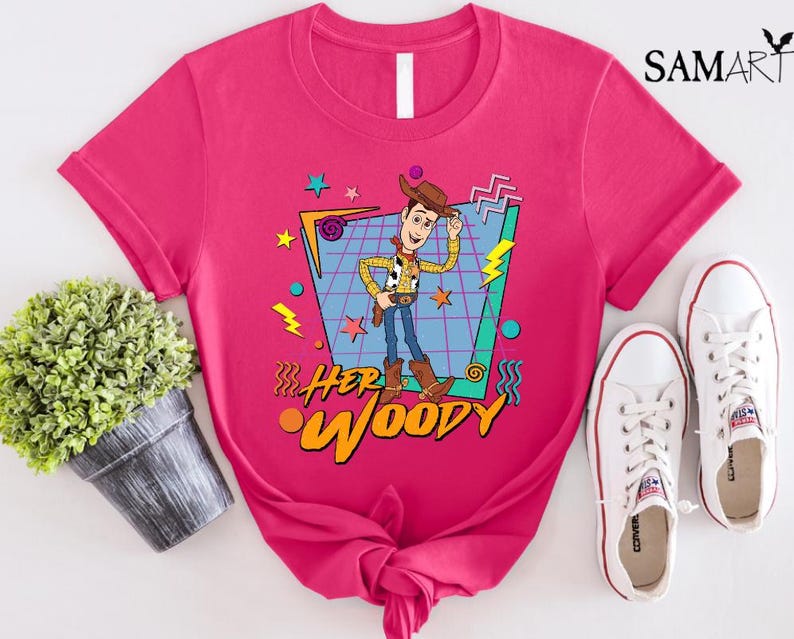 以下が含まれることがあります： トイストーリーのウッディの漫画の画像が描かれた、レトロな90年代のデザインのピンクのTシャツ。Tシャツには「Her Woody」という文字がプリントされています。