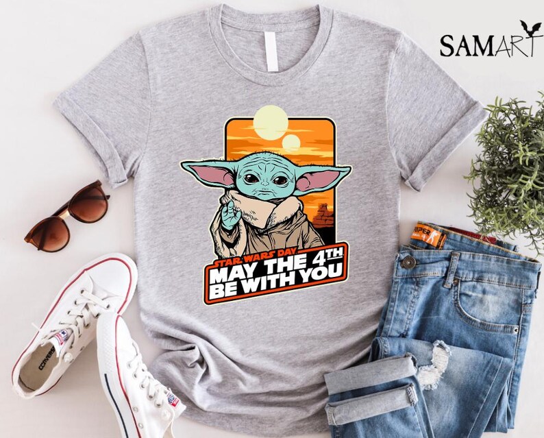 May include: A gray t-shirt with a cartoon image of a green alien character with big ears. The text "Star Wars Day May the 4th Be With You" is printed on the shirt.