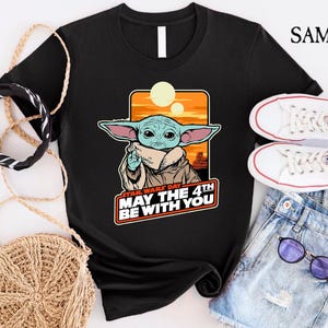 May include: Black t-shirt with a graphic of a green alien character with large ears. The text "Star Wars Day May the 4th Be With You" is printed below the character.
