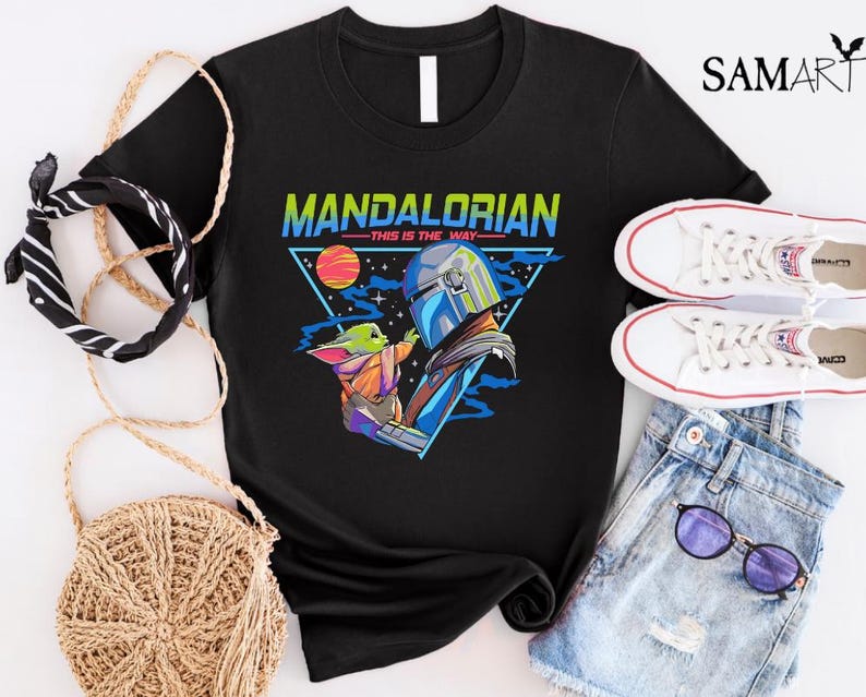May include: Black t-shirt with a retro-style graphic of the Mandalorian and Grogu. The graphic features the text "Mandalorian - This is the Way" in a colorful font.