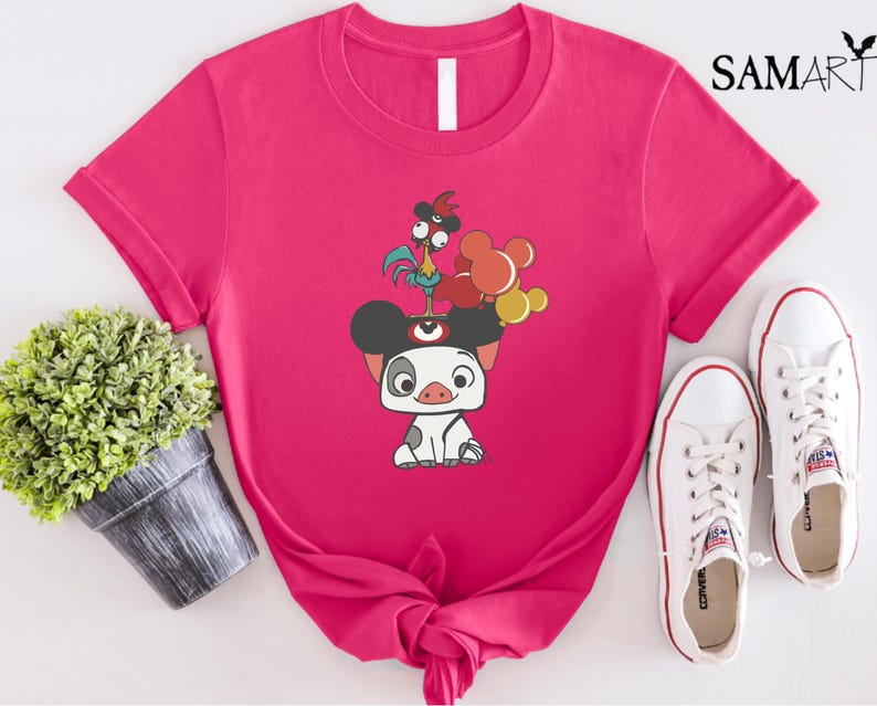 May include: A hot pink t-shirt featuring a cartoon illustration of a pig with a rooster and balloons. The shirt has a crew neck and short sleeves. White sneakers are next to the shirt. The text "SAMART" is in the upper right corner.