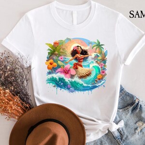 Pode incluir: Camiseta branca com uma ilustra&ccedil;&atilde;o colorida de uma mulher em um cen&aacute;rio tropical. O design inclui uma mulher com top e saia vermelhos, cercada por flores, ondas e palmeiras. A marca "SAMART" est&aacute; impressa no canto superior direito.