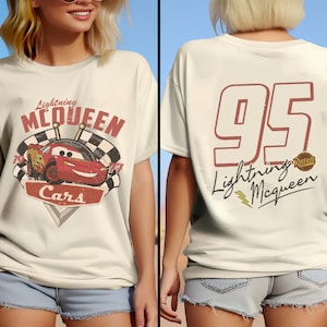 Op de afbeelding: Een wit T-shirt met een rode en zwarte afbeelding van Lightning McQueen uit de film Cars. De afbeelding bevat de tekst "Lightning McQueen" en "Cars". De achterkant van het shirt heeft een rood nummer 95 met de tekst "Lightning McQueen" en een Rust-eze-logo.