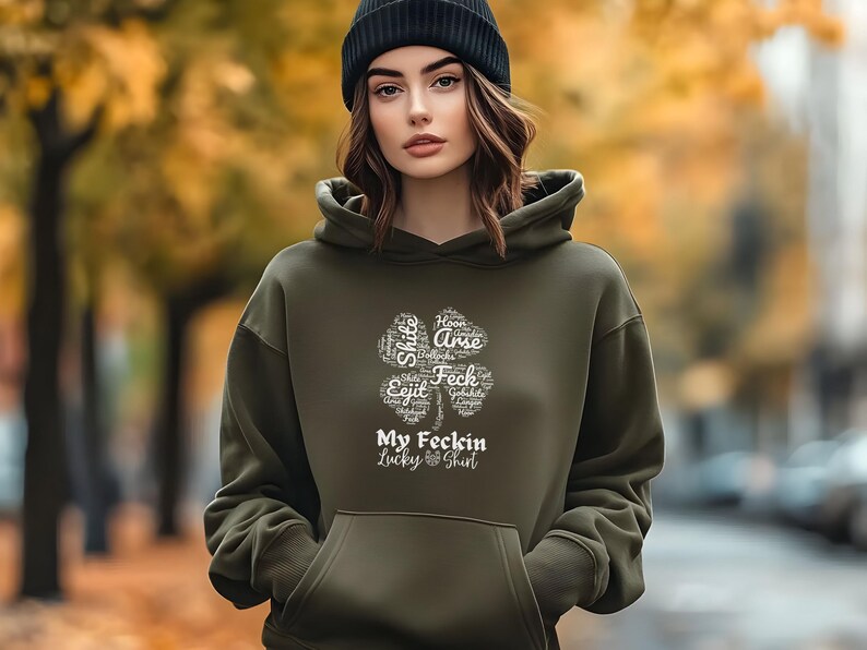May include: A dark green hoodie with a white four-leaf clover graphic. The clover is made up of words, including "Feck" and "Arse". The text "My Feckin Lucky Shirt" is below the clover.