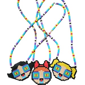 May include: Three beaded necklaces with Powerpuff Girls character charms. The necklaces are made with colorful beads and have the words "POWERPUFF GIRLS" spelled out on them.