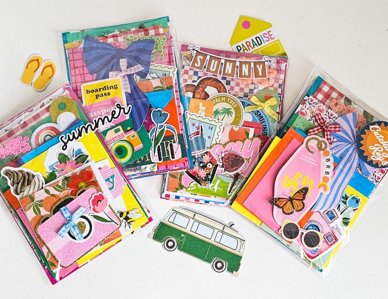 May include: Several clear plastic pouches filled with colorful summer-themed ephemera. Each pouch contains stickers, tags, and decorative paper with images of cameras, flowers, and travel motifs. The word "summer" is written on one pouch.