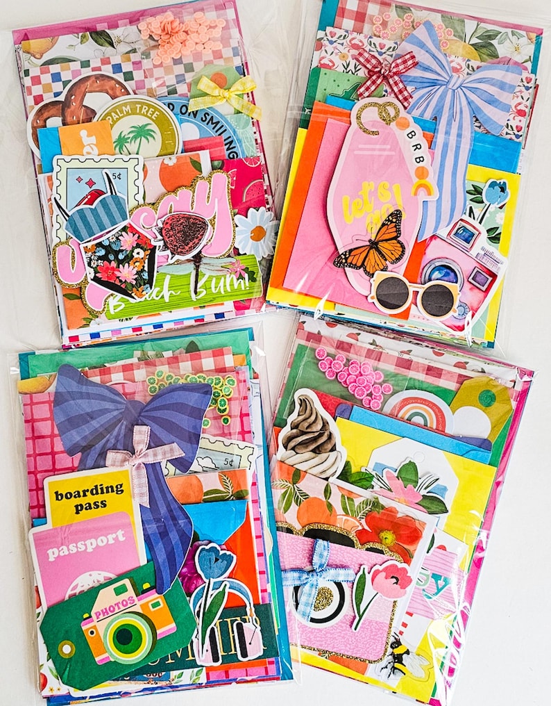 May include: Four colorful scrapbook kits in clear plastic packaging. Each kit features decorative paper, stickers, and embellishments with travel and summer themes. Designs include bows, butterflies, cameras, and the text "Beach Bum."