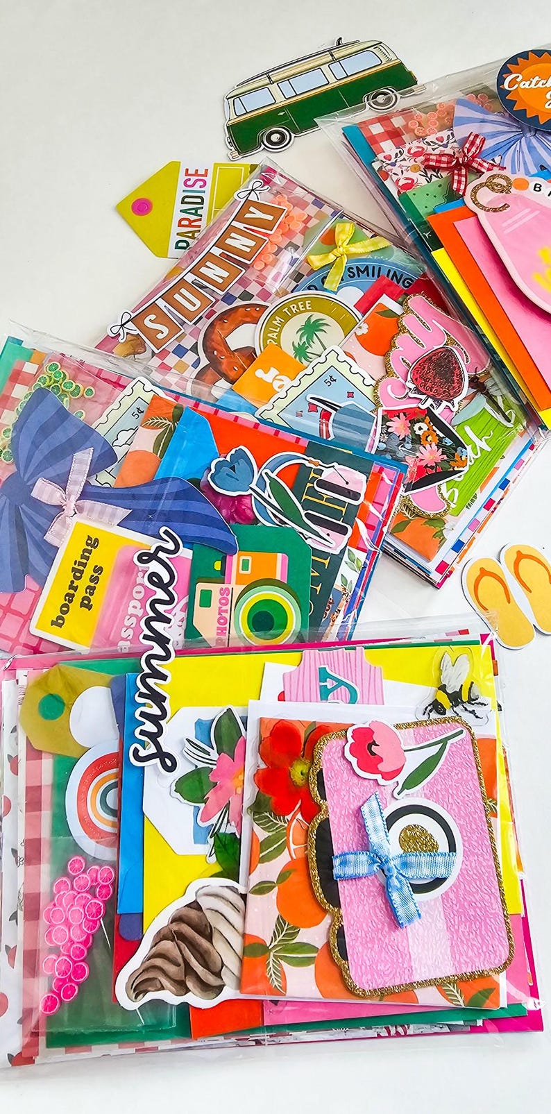 May include: A collection of colorful summer-themed stickers and tags, including a green van, a pink surfboard, and the word "Sunny". Other stickers feature palm trees, flowers, and the word "Summer". The items are in clear plastic bags.