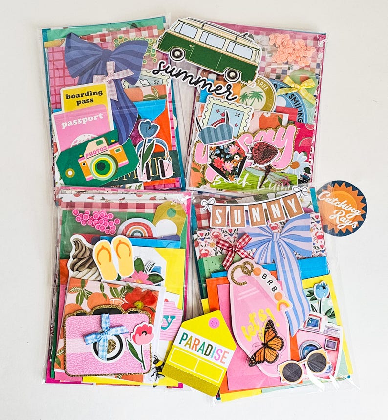 May include: Four clear plastic pouches filled with colorful travel-themed ephemera. Each pouch contains decorative paper, stickers, and die-cuts with summer and vacation motifs, including cameras, passports, and a green camper van.