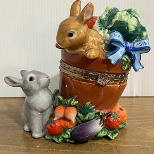 May include: A white ceramic mug with a black handle and the text "But First, Coffee" in a bold, black font. The mug is displayed on a white surface, showcasing its clean design.