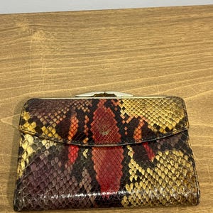 May include: A vintage snakeskin wallet with a gold clasp. The wallet is multi-colored with shades of brown, red, yellow, and black.