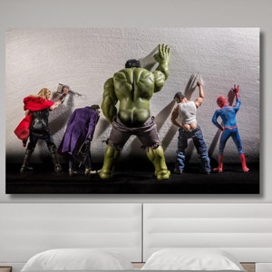 May include: A group of five action figures, including Hulk, Spider-Man, and Thor, are standing in a row facing a white wall. The figures are all in different poses, and some are holding weapons. The figures are all made of plastic and are painted in bright colors.