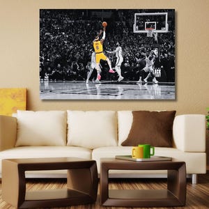 Op de afbeelding: Een rechthoekige canvas print voor aan de muur met een zwart-witfoto van een basketbalwedstrijd. Een speler in een geel shirt met het nummer 6 springt om de bal naar de basket te schieten, omringd door andere spelers op het veld.