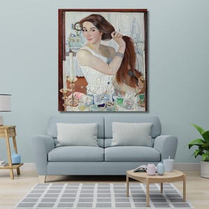 May include: A framed oil painting depicting a person with long reddish-brown hair wearing a white sleeveless top. The person is shown from the chest up, looking toward the viewer while styling their hair. Various vanity items are visible on the table.