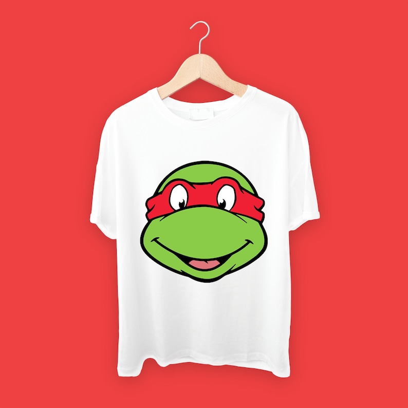 May include: White t-shirt with a green and red cartoon face of a Teenage Mutant Ninja Turtle wearing a red mask.