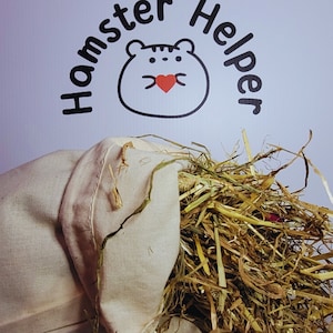 May include: A white canvas bag filled with dried hay. The bag is lying on a white surface with the text "Hamster Helper" above it.
