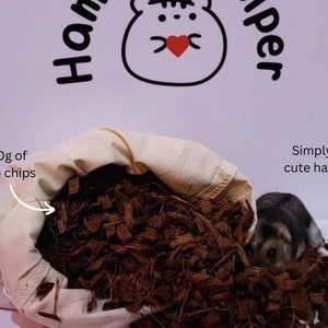 May include: A white canvas bag filled with 100g of brown coco chips. A small hamster is peeking out from the bag of chips. The text "100g of coco chips" and "Simply add cute hamster!" are written on the image.