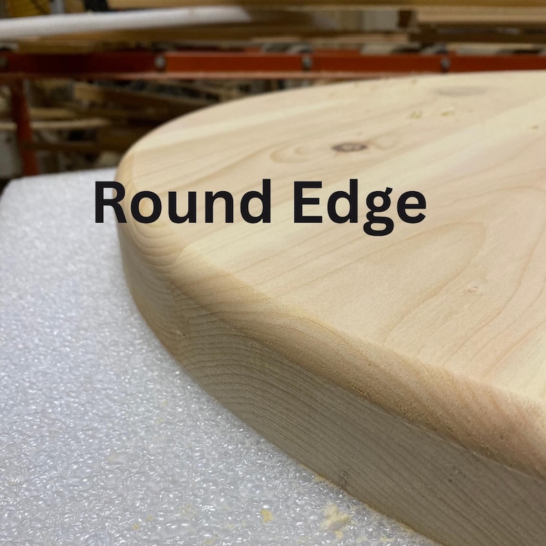 May include: Close-up of a light-coloured, unfinished wooden surface with a rounded edge. The text "Round Edge" is printed in black across the top of the image. The wood grain is visible, and the surface appears smooth.