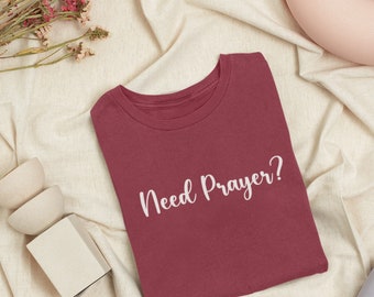 Peut inclure: Un t-shirt marron avec le texte "Need Prayer?" imprimé en blanc sur le devant.