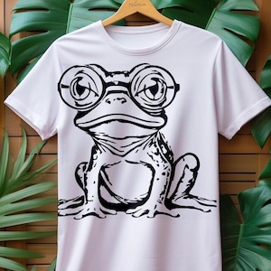 Puede incluir: Camiseta blanca con una ilustración en blanco y negro de una rana con gafas redondas.