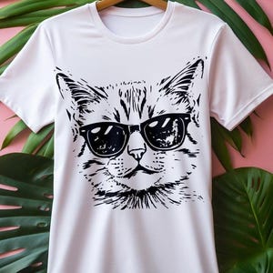 May include: White t-shirt with a black and white illustration of a cat wearing sunglasses.