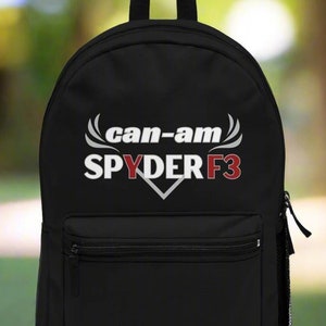 Puede incluir: Mochila negra con un logotipo blanco "can-am SPYDER F3" en una fuente blanca estilizada. El logotipo tiene acentos rojos.