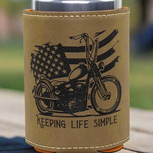 May include: A brown leather can cooler with a black silhouette of a motorcycle and an American flag design. The text "KEEPING LIFE SIMPLE" is printed on the cooler.