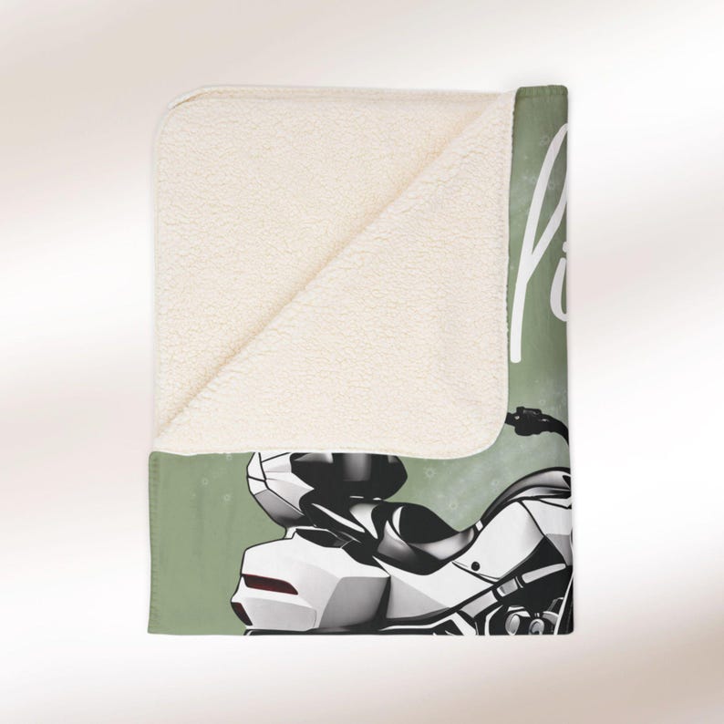 May include: A green and white fleece blanket featuring a motorcycle illustration and the text "Ride" on it.