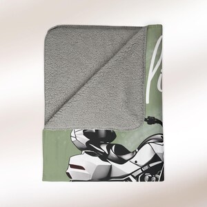 May include: A green and white fleece blanket featuring a motorcycle illustration and the text "Ride Free".